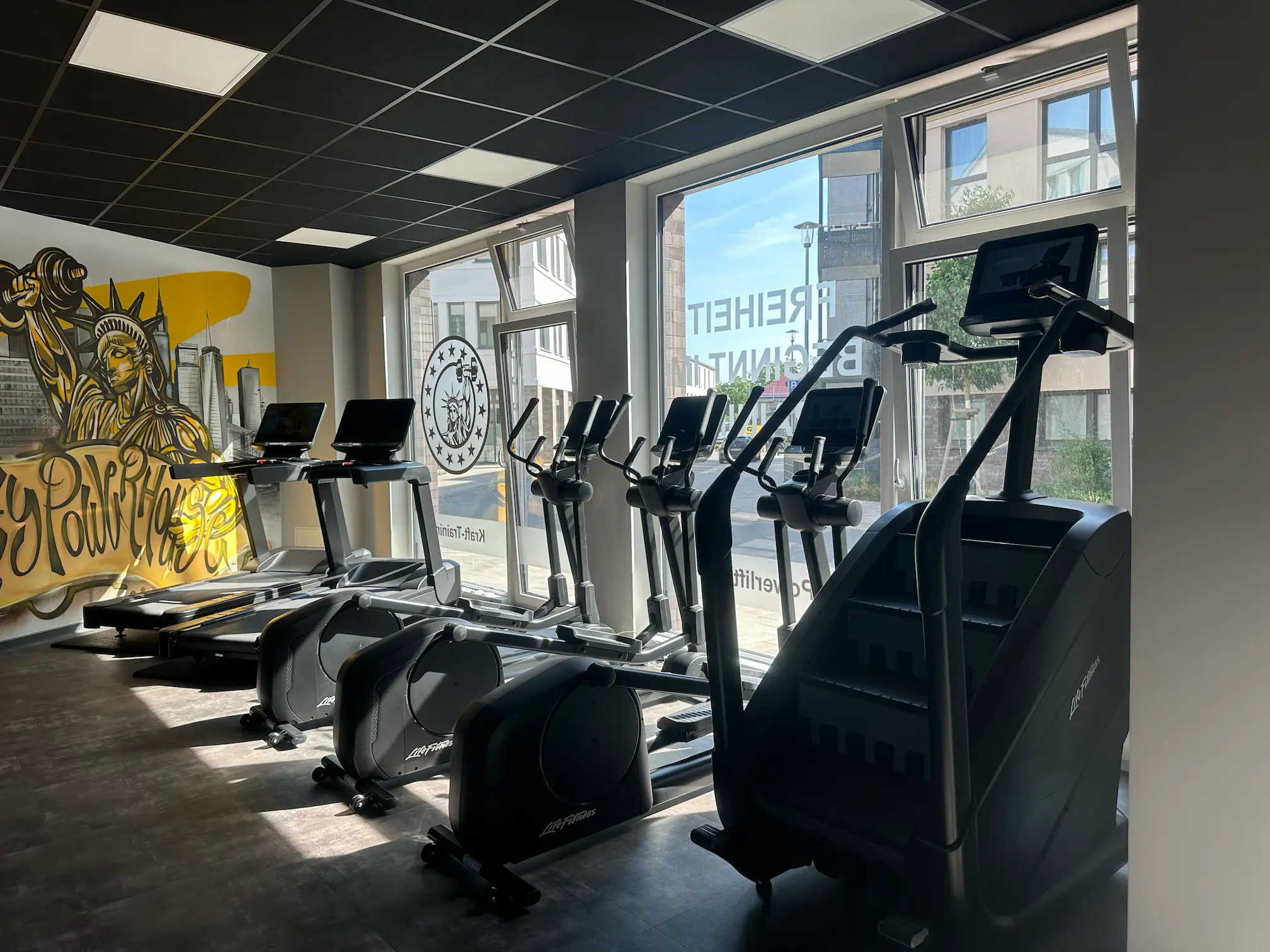 Moderner Cardio-Bereich im Liberty Powerhouse Gym Michendorf mit Life Fitness Geräten und großen Screens.